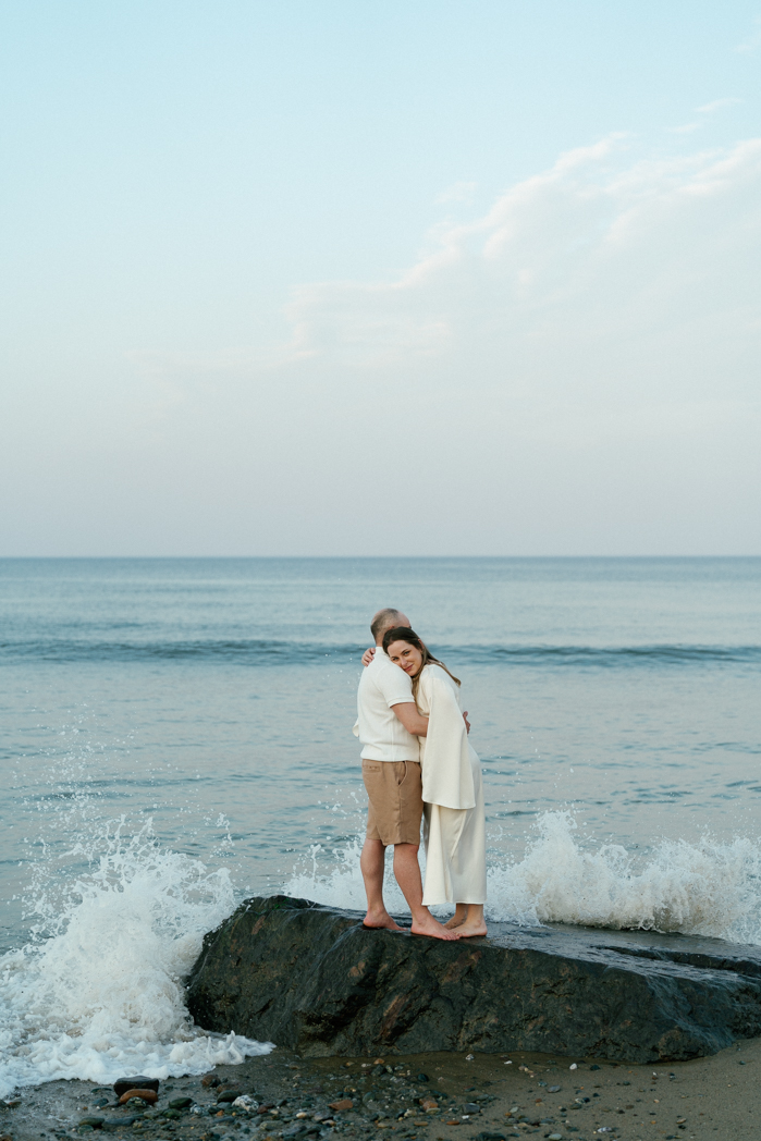 Couple standing on rocks at Nauset Lighthouse Beach during a photo session on Cape Cod